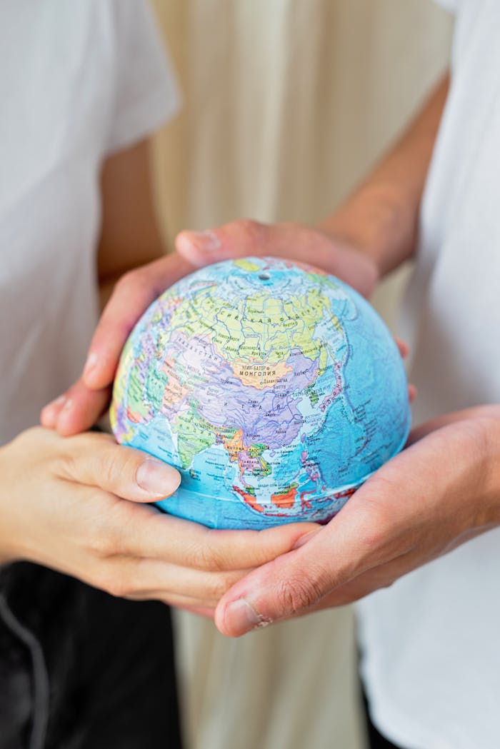 Two adults holding a colorful globe in their hands, representing global unity and environmental awareness.