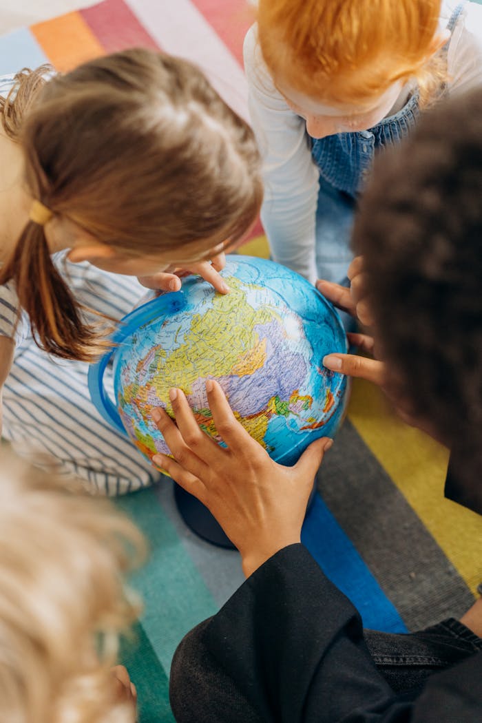 A diverse group of children examining a globe, viewed from above.